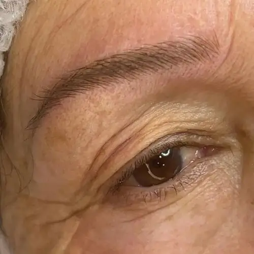 Un ojo con ceja arqueada, piel arrugada y poros visibles.